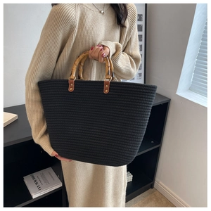 Detail of hand-woven black tote bag featuring authentic natural bamboo top handles