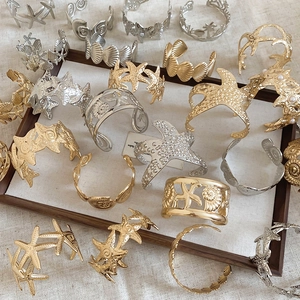 Collection of gold and silver starfish and shell bangles displayed on a linen tray