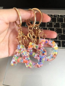Detail of A, B, D initial keychains with colorful heart sequins in clear resin