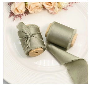 Macro view of olive green frayed edge silk ribbons wound on rustic wooden spools