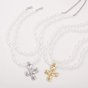 Detail showing cross pendants with irregular rock texture on pearl necklaces