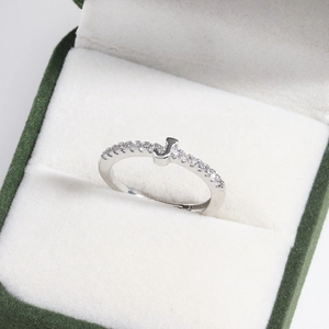 Macro shot of silver J-letter ring with diamonds in a green velvet gift box