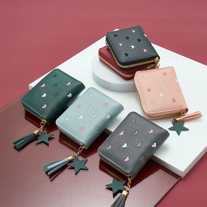 Close-up of heart-embroidered short wallets with zippers and decorative star tassels