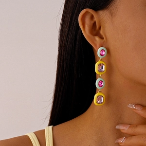 Detail of colorful geometric drop earrings with mint green enamel and pink crystals