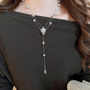 Detail of layered silver necklace featuring star pendant, grey pearls, and crystal droplets