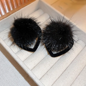Macro shot of black fuzzy heart earrings in a plush jewelry box with soft fur texture