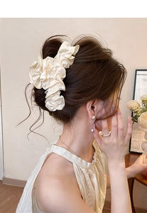 Detail of cream pleated fabric hair claw clip worn in a romantic updo hairstyle