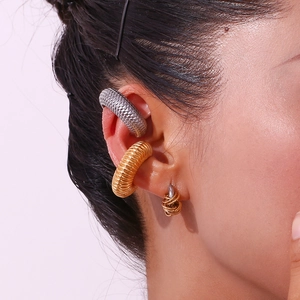 Detail of twisted C-shaped earrings and metal ear cuffs in gold and silver finish