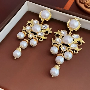 Close-up of luxury Baroque earrings with gold metal, pearls and crystals in a jewelry box