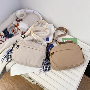 Detail of cream and khaki nylon crossbody bags with checkered charms and fashion label