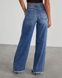 Détail d'un jean large à taille haute montrant l'ourlet brut et la texture denim délavé