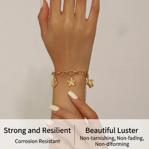 Detail of gold-plated stainless steel chain bracelet with sea shell and starfish charms