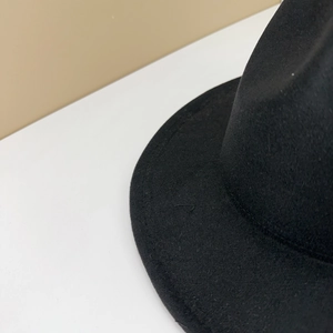 Close-up of the stitching details and high-quality wool felt texture of a black fedora hat