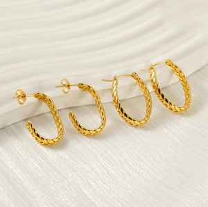 Detailed view of vintage gold-plated hoop earrings with twisted texture on white platform