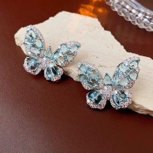 Detailed macro view of silver butterfly earrings with blue zircon and pearls