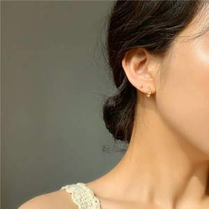Close-up of golden chain style 925 silver earrings worn on ear in soft light
