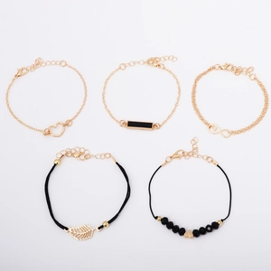 Detailed macro view of 5-piece gold bracelet set with black beads and infinity leaf charms