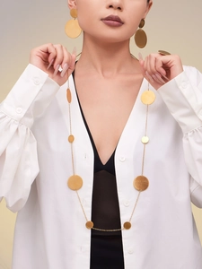 Vue détaillée du long collier doré et des boucles d'oreilles sur un mannequin