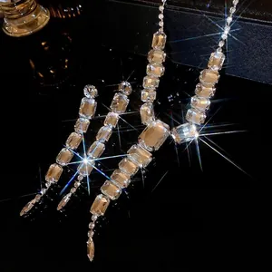 Elegant square crystal necklace and tassel earrings set on reflective black background