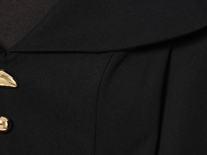 Detail of elegant V-neckline featuring unique gold metal buttons on premium black fabric