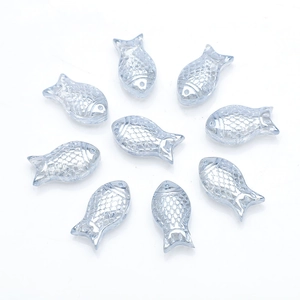 Macro detail of transparent light blue fish-shaped glass charms with scale texture