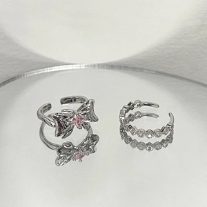Macro shot of a silver bow ring with pink zircon and a matching sparkling band ring