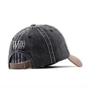 Detail of washed denim baseball cap featuring white contrast stitching and embroidery