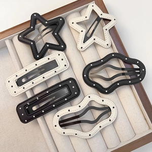 Close-up of PU leather star and geometric hair clips with silver polka dots in a box