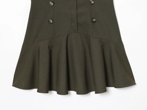 Detail view of dark green dress hem featuring elegant buttons and ruffled fishtail design