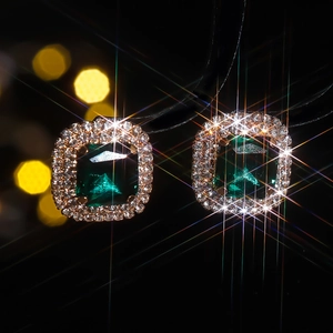 Macro detail of emerald cut green gemstone earrings with double halo diamond setting