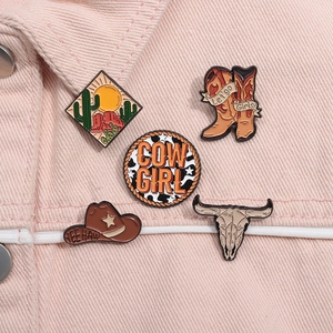 Enamel cowboy pins set on pink denim background including boots and desert designs