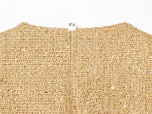 Dettaglio macro del colletto in tweed dorato con paillettes ed etichetta taglia XS