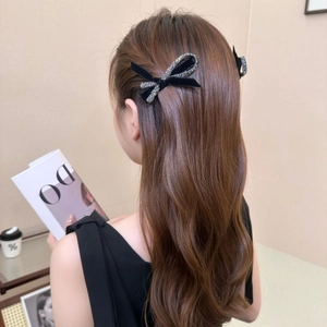 Pair of elegant black velvet bow hair clips with silver rhinestones on long wavy brown hair