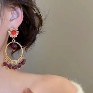 Detail of vintage bohemian tassel earrings with red stone and purple beads on model