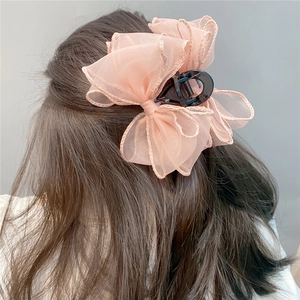 Close-up of pink organza bow hair claw clip styled on a woman's half-up hairstyle