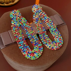 Detailed macro view of vintage gold chain earrings with colorful zircons on a gift box