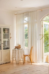 Detail of cream striped embroidered curtain with tassels showing breathable fabric texture