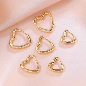 Detailed view of various sizes of gold heart-shaped hoop earrings on silk fabric