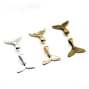 Detail of whale tail charms in silver, gold, and bronze finishes for DIY jewelry