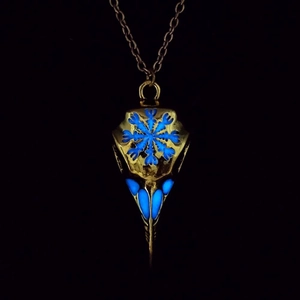 Close-up of a bronze Viking crow skull necklace with glowing blue eyes in the dark