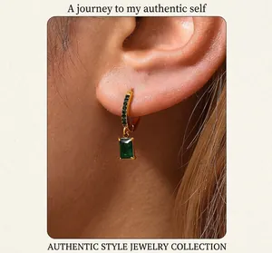 Macro shot of 18K gold-plated earrings with emerald green rectangular cubic zirconia