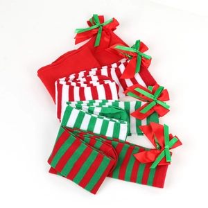Detail of Christmas over-knee socks with festive bow ties and striped knit patterns