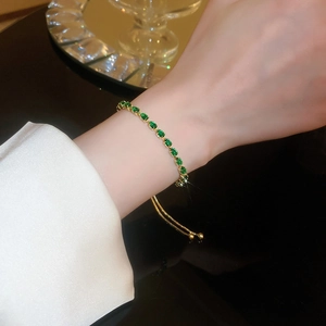 Close-up of gold plated pearl bracelet with green gemstones on a model's wrist