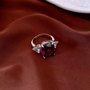 Detail of a silver open ring featuring a deep purple rectangular stone and side zircons