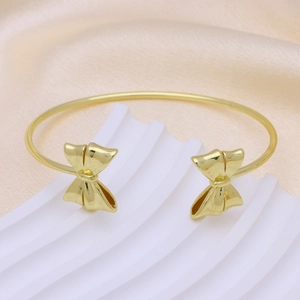 Polished 18k gold plated bow knot open cuff bracelet on white minimalist display