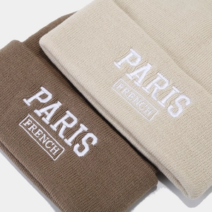 Brown and beige knitted beanies with white PARIS and FRENCH embroidery on light background