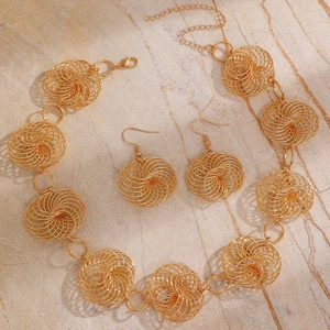 Detail of woven spiral gold jewelry set including necklace and earrings on marble