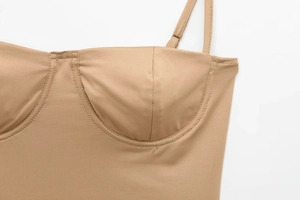 Detailopname van een nude satijnen bodysuit met verstelbare bandjes en cups