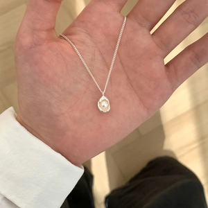 Minimalist silver necklace with pearl butterfly pendant held in hand for scale