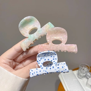 Detail view of acetate hair claws in pastel marble, pink pearl, and polka dot patterns